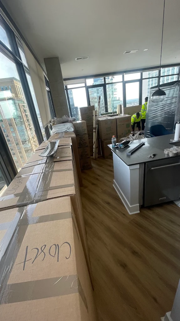 Labeled boxes lining a high-rise penthouse with the crew wrapping in the background