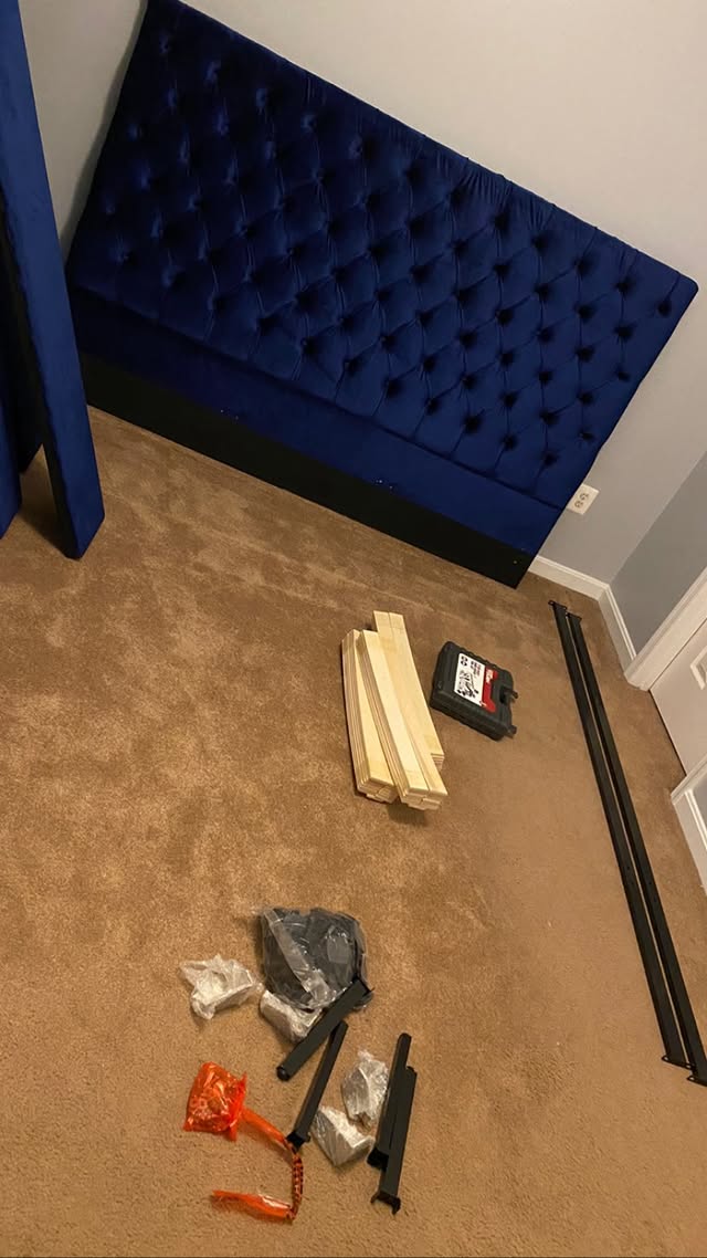 Blue tufted headboard with hardware laid out on the carpet