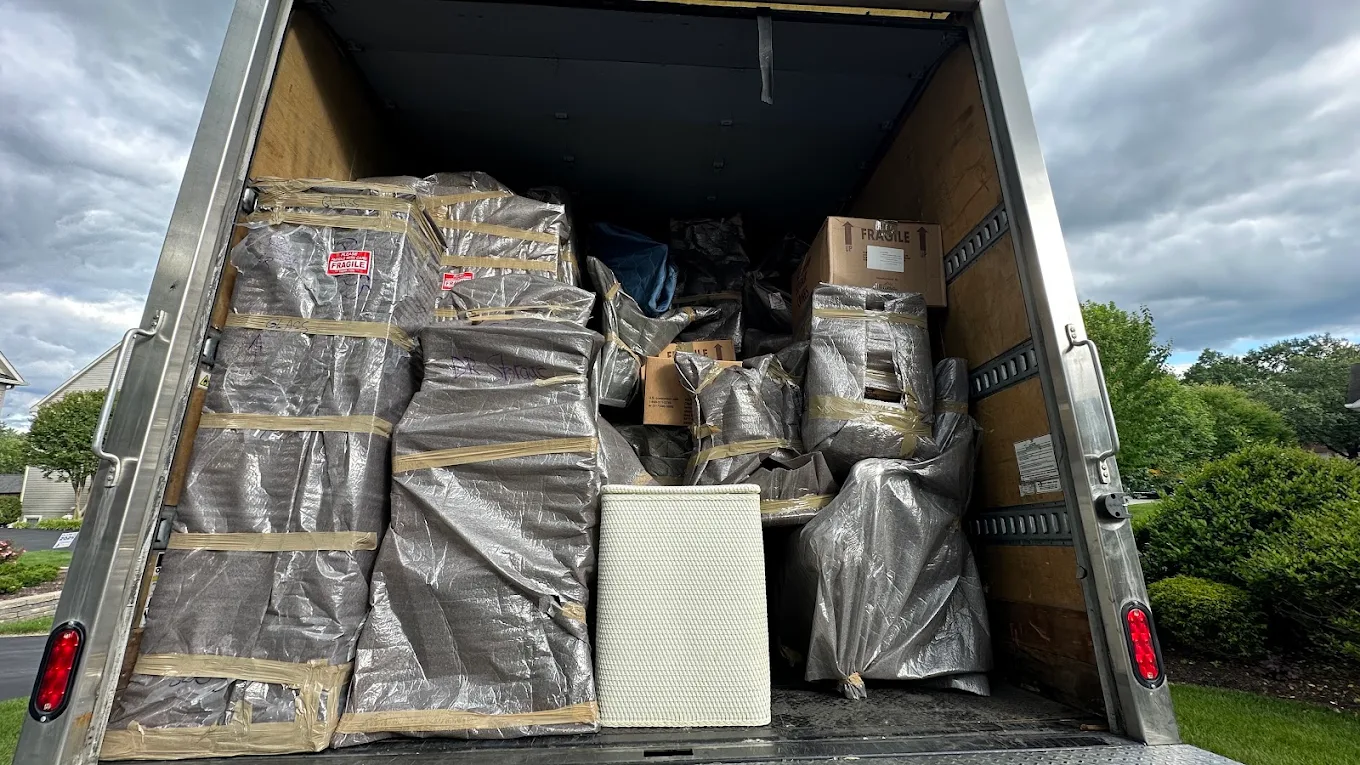 A fully loaded truck with silver-wrapped fragile furniture strapped in tiers