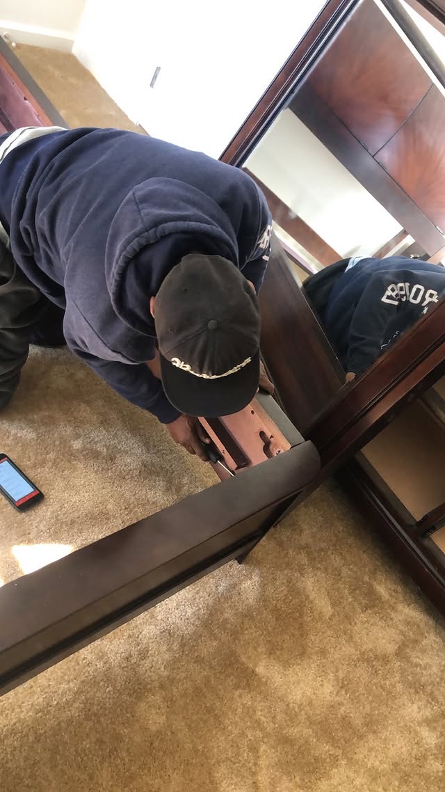 Mover taking down a heavy wooden bed frame