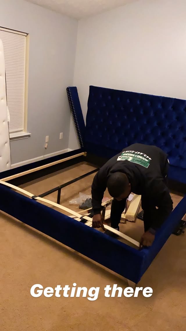 Mover assembling a blue velvet tufted bed frame